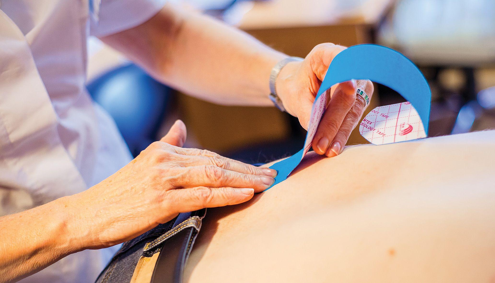 terapeutka aplikuje kinesiotaping